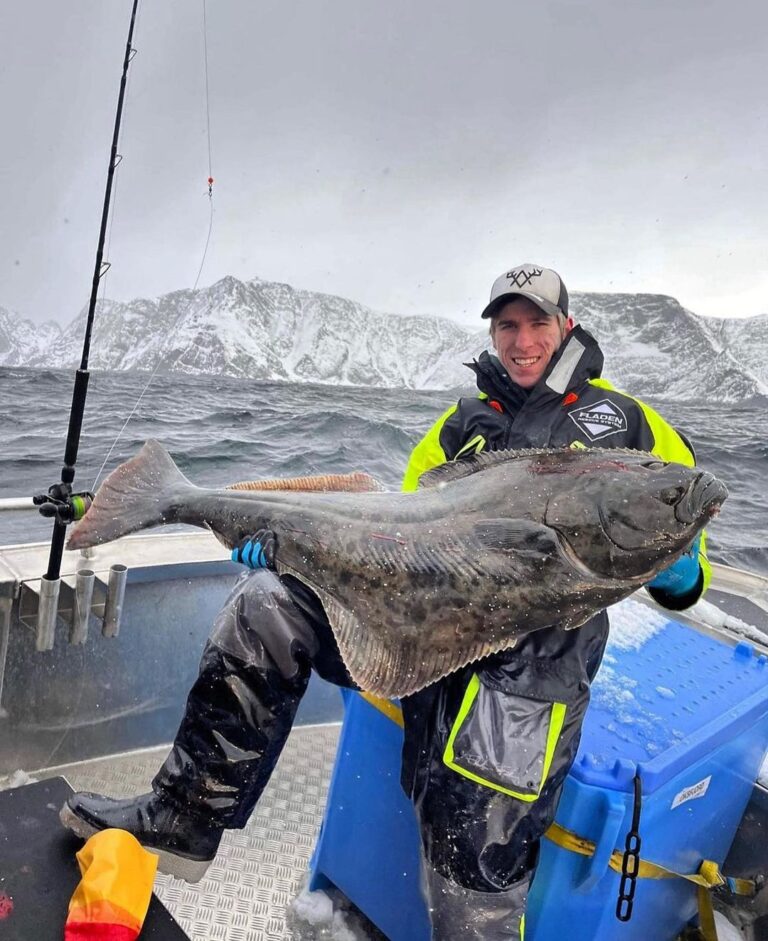 En glad fiskeelev som sitter i en båt i den vintriga sjön och håller fram sin fångst - under sin praktik i Norge där han jobbade med ishavsfiske, under utbildningen inom sportfisketurism på Fiskegymnasiet i Älvdalen.