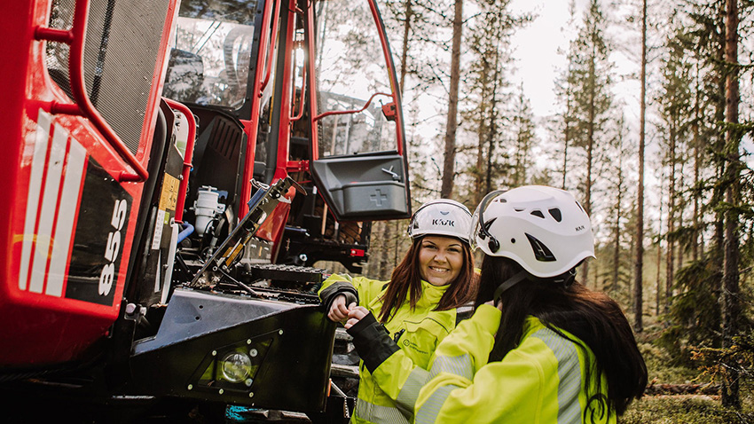 Skogsgymnasiet - två elever som står i skogen vid en skogsmaskin